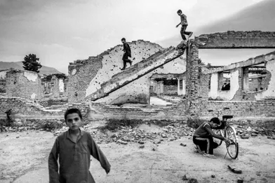 Afghan boys play in the ruins from war in center of Kabul.