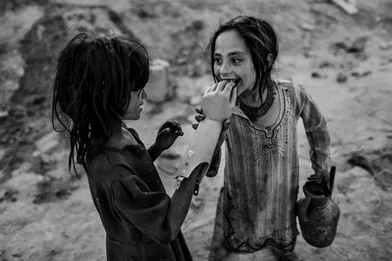 Two Afghan girls play with an artificial hand, south of Kabul.