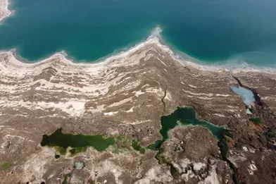 La mer Mortea perdu un tiers de sa surface depuis 1960.Les eaux bleues se retirent d'environ un mètre chaque année, laissant derrière elles un paysage lunaire, une terre blanchie par le sel etperforée de trous béants.