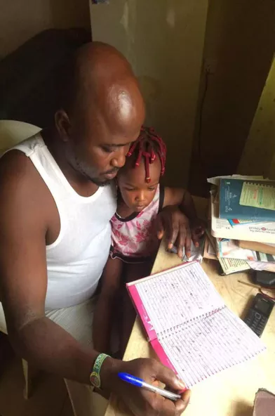 Obi C. Kingsley et sa fille, Special, en train d'écrire son téoignage à Benin City. 
