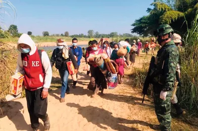 Des soldats thaïlandais accueillent les villageois qui ont fui les combats entre l’armée birmane et la rébellion karen, fin décembre.