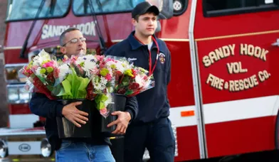 Des pompiers du quartier de Sandy Hook apportent des fleurs à l'école élémentaire où les meurtres ont été commis.