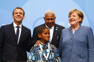 Emmanuel Macron, le Premier ministre fidjienFrank Bainimarama, la chancelière allemande Angela Merkel et le petit TimothyNaulusalaau World Convention Center de Bonn pour la COP23, en début d'après-midi le 15 novembre 2017.