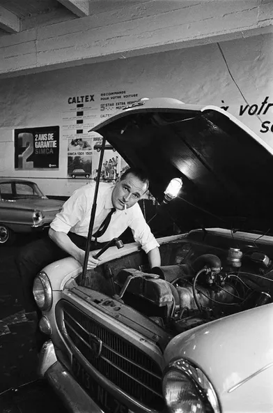 14 avril 1967.Jacques Chirac, nouveau ministre du Travail, fumant une cigarette en bricolant dans le moteur de sa voiture modèle Peugeot 403, dans un garage.