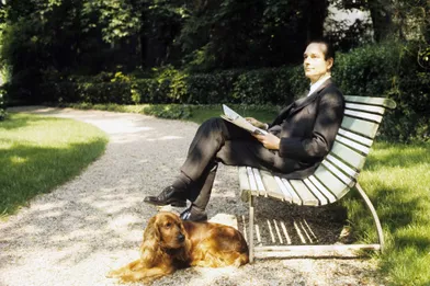 Dans les jardins de Matignon, le nouveau Premier ministre Jacques Chirac, qui a pris ses fonctions le 27 mai 1974, en costume cravate, assis sur un banc avec un journal, son chien cocker couché près de lui.