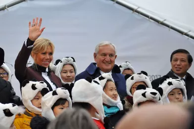 Des enfants avec des bonnets panda entourent Brigitte Macron, Jean-Pierre Raffarin etZhang Yesui.
