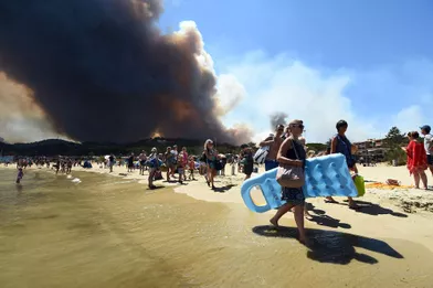 Des touristes quittent la plage alors que le feu brûle la forêt àBormes-les-Mimosas