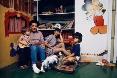 Coluche lors d'une séance photo en famille, avec son épouse Véronique et leurs fils Marius, 4 ans, et Romain, 8 ans, chez eux, rue Gazan, près du parc Montsouris, dans le XIVe arrondissement de Paris, en octobre 1980.