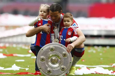 Daniel Van Buyten, joueur du Bayern Munich, pose avec le trophée remporté par son équipe et ses deux enfants. 