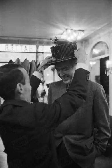 James Stewartportant l'appareil à mesurer le tour de tête chez un chapelier, lors d’un passage à Paris en novembre 1959.