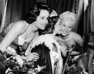 Claudine Auger (à g.) pose avec Miss Monde 1958, la Sud-Africaine Penelope Coelen dont elle a été désignée la 1ère Dauphine, à l'issue du concours qui s'est tenu à Londres le 13 octobre 1958. À droite, la 2ème Dauphine, la Danoise Vinnie Ingemann.