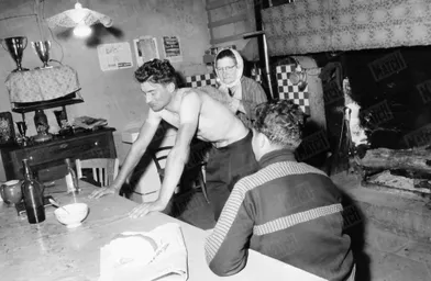 Revenue à de meilleurs sentiments sur le vélo, sport qu'elle jugeait dangereux, la mère de Poupou passe un gant de crin dans le dos de son champion fourbu, en mars 1961.