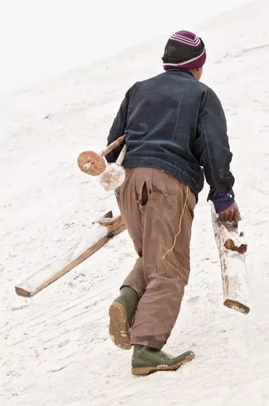 Sayed Ali prend ses bâtons sous le bras et les skis à la main. Au sommet, il bricole une ficelle qui servira de fixation.