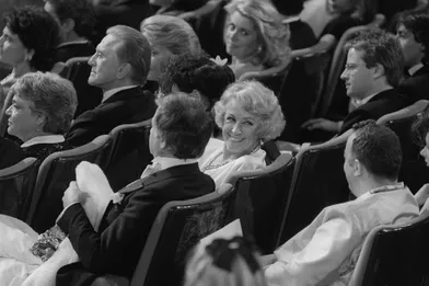  L'actrice Danielle Darrieux sourit après avoir reçu un César d'Honneur, lors de la 10ème cérémonie des Césars au Théâtre de l'Empire, le 02 mars 1985, à Paris. Elle est entourée de Simone Signoret, Kirk Douglas, Catherine Deneuve, Christophe Lambert, Coluche. 