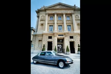 Devant la façade de l’Hôtel de Crillon dessinée, comme toute la place de la Concorde par Jacques-Ange Gabriel, l’architecte de Louis XV, la DS Palace de collection, voiture de courtoisie pour promener les clients dans Paris.