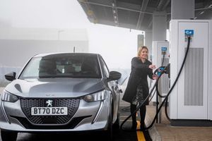 Une femme recharge sa Peugeot électrique. 