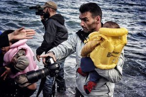 Son appareil photo dans une main, un bébé dans l'autre, Aris Messinis est partagé entre ses deux devoirs: informer et aider. 