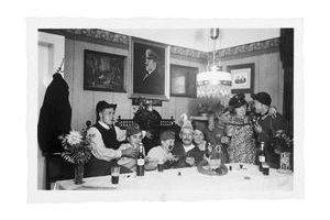  Sous le portrait du Führer. Soldats et sous-officier fêtent une permission. Dans la salle à manger, le cadre du dictateur fait pendant à celui des vieux parents.