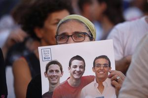 Une femme porte les photos des trois jeunes Israéliens pendant une mobilisation à Tel Aviv, en juin dernier.