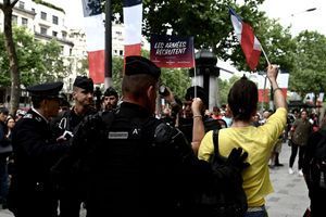 Une femme en jaune, appartenant au mouvement des Gilets jaunes, est entourée par les forces de l'ordre alors qu'elle interpelle Emmanuel Macron lors de son examen des troupes sur les Champs-Élysées. 