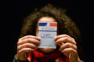 Femme tenant une carte électorale française, le 19 mars 2017.