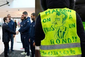 Emmanuel Macron salue les joueurs de l'équipe de France de handball, mercredi à Créteil. A droite, un "gilet jaune" participant au rassemblement anti-Macron organisé à proximité.