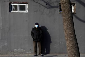 Un homme portant un masque pose dans une rue de Chine.