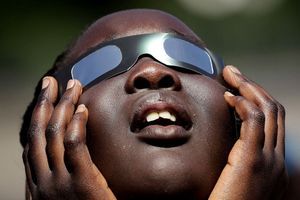 Un enfant s'entraîne à utiliser ses lunettes pour observer l'éclipse. 