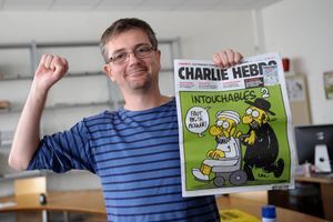 Charb, caricature à la main et poing levé, le 19 septembre 2012. Le dessinateur et patron de Charlie Hebdo a été assassiné mercredi, avec 11 autres personnes. 
