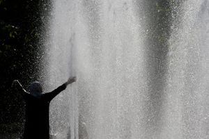 Un homme profite des fontaines du Trocadéro à Paris pour se rafraîchir. 