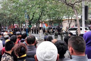La foule regarde les secours et les autorités devant le marché d'Urumqi après le drame jeudi matin. 
