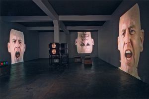 Une installation vidéo composée de trois écrans très grand format affiche le visage d’un homme épelant continuellement : « Feed me/Eat me/Anthropology »