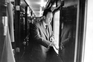 Albert Camus, prix Nobel de littérature en 1957 pour l'ensemble de son oeuvre, part en Suède en train pour recevoir le prix : attitude de l'écrivain debout dans un couloir, regardant par une vitre.