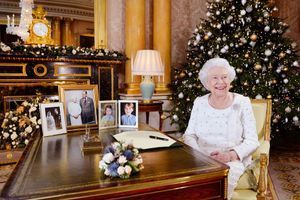 La reine Elizabeth II pose dans son bureau, où se trouvent deux portraits de son époux et elle, et deux photos des petits George et Charlotte.