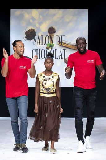 Laurent Maistret et Namadia Thaï Thaï, de «Koh-Lanta», défilent avec Emerisca, une jeune fille ayant reçu une greffe du coeur grâce à Mécénat Chirurgie Cardiaque, au Salon du Chocolat à la Porte de Versailles à Paris le 27 octobre 2021