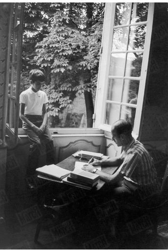 Valéry Giscard d'Estaing écrit à sa table de travail en présence de son fils Henri, 10 ans, dans la maison familiale du Puy-de-Dôme, en août 1967.