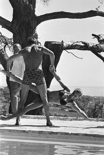 Tournage du film "La piscine" de Jacques DERAY dans le décor d'une somptueuse villa aux environs de Saint-Tropez pourvue d'une immense piscine : Alain DELON de dos portant à bout de bras Romy SCHNEIDER par une jambe et un bras avant de la jeter dans la piscine.
