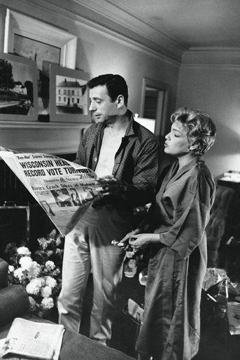 Yves Montand et son épouse, Simone Signoret, lisent un journal dans leur chambre d'hôtel, au lendemain de la cérémonie de remise des Oscars.