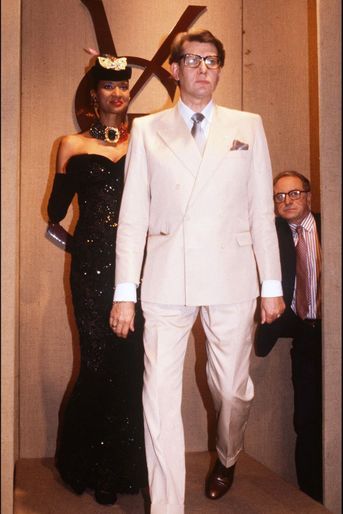 Au fond, à droite, Pierre Bergé veille sur Yves Saint Laurent qui fait son entrée pour saluer le public à l'issue du défilé, en juillet 1984, de présentation de sa collection haute-couture automne-hiver 1984-1985. 