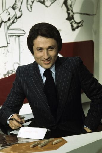 En novembre 1975. L'animateur préféré des Français, tout sourire et stylo en main, assis dans le décor de l'émission "Le Petit Rapporteur"