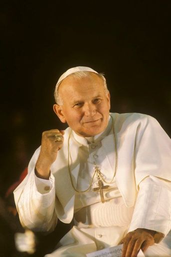 Juin 1980, en FRANCE, sa Sainteté le Pape JEAN-PAUL II vêtu de blanc, portant la calotte balnche, arborant la Croix, assis.