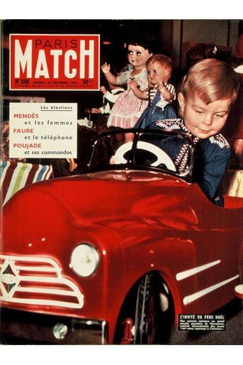Couverture du Paris Match n°350 du 24 décembre 1955 : un enfant jouant au volant d'une petite voiture rouge au milieu d'autres jouets au marché populaire de Nuremberg.