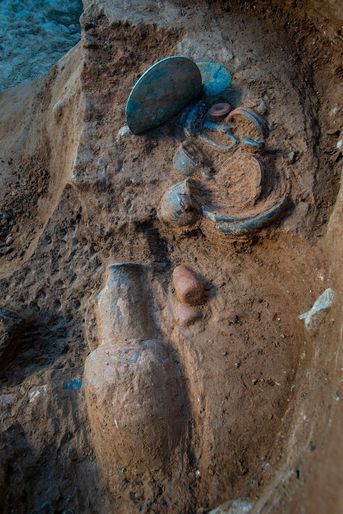 Poteries, objets en bronze et miroir en cours d'exhumation dans une tombe étrusque.