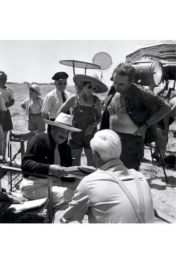 À l’été 1951, le cinéaste tourne « Le salaire de la peur » dans l’ancien camp d’internement de Saliers. La scripte, les techniciens et le réalisateur entourent l’acteur Charles Vanel. Face à lui, de dos, son partenaire Peter van Eyck.