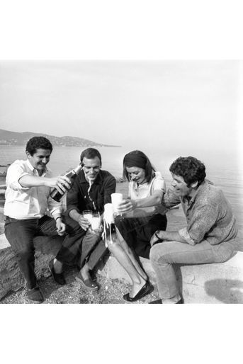 Pour fêter la consécration cannoise d&#039;«Un homme, une femme», en mai 1966, Jean-Louis Trintignant, Claude Lelouch, Pierre Barouh et  Anouk Aimée sabrent le champagne. 