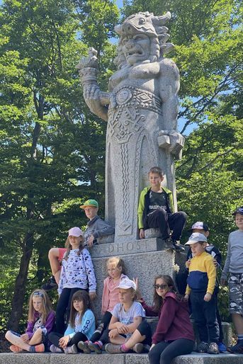Un groupe d’enfants pose au pied de la statue du dieu Radegast.
