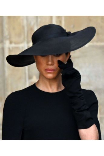 La duchesse de Sussex, les yeux embués derrière son large chapeau. 