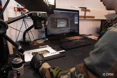 Un technicien de la Direction du renseignement militaire analyse un smartphone.