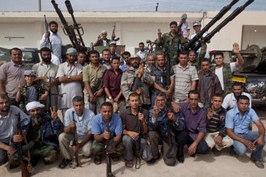 Samedi 22 octobre, à Misrata, le groupe de combat Khatibat al-Khirane. Au centre, en veste camouflage avec un chapeau, le commandant de la brigade. Les hommes qui ont capturé Kadhafi se tiennent à ses côtés. Trois à sa droite, dont l’un tient la kalachnikov du Guide, trois à sa gauche. Exhibée en trophée sur le canon de fusil, la bottine du colonel.