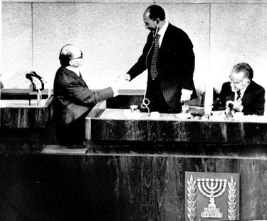 Le président égyptien Anouar el-Sadate, debout, serre la main du Premier ministre israélien Menahem Begin, après son discours devant la Knesset, le Parlement israélien, le 19 novembre 1977.
